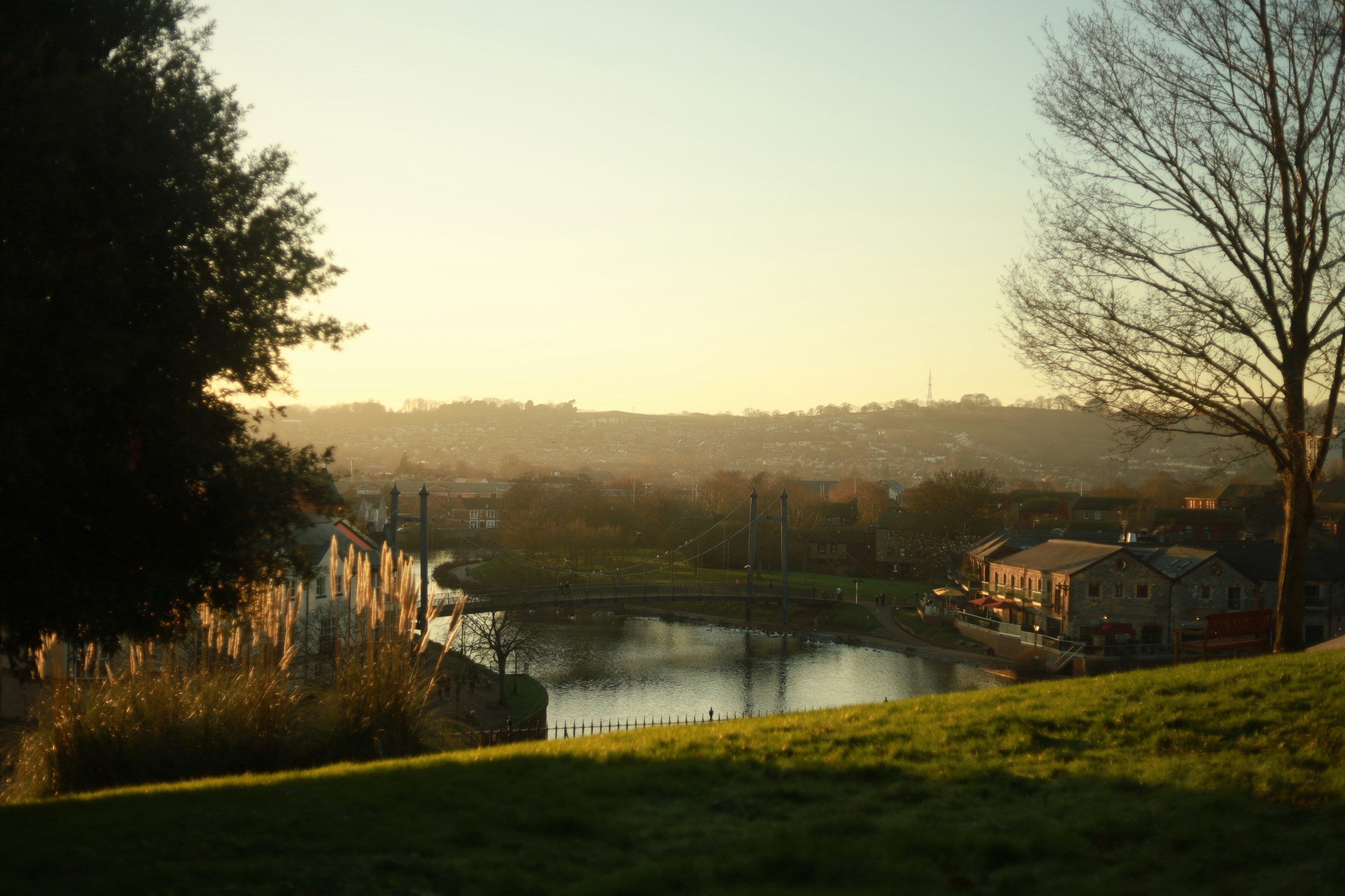 Scenic view of a river exe with buildings and trees at sunset.